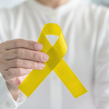 Yellow ribbon symbolic color for suicide prevention and Sarcoma Bone cancer awareness in person's hand