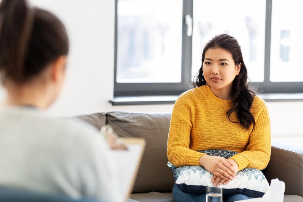 A young woman speaks with her therapist in psychotherapy treatment for bipolar disorder.